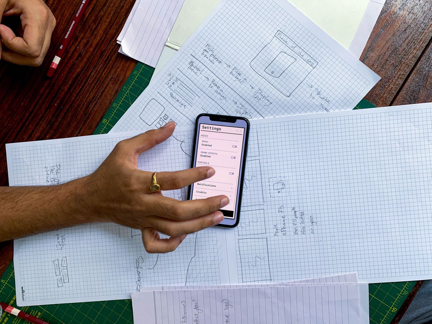 Hand on a smartphone over app wireframe sketches