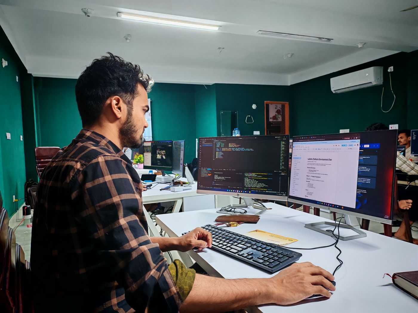 Developer working at a desk with two monitors in an office